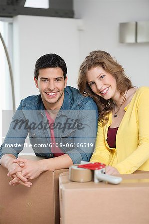 Couple leaning over cardboard boxes and smiling