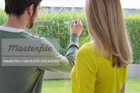 Woman looking at an architect drawing a design on the window glass