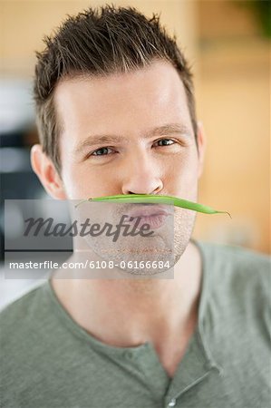Man making artificial mustache with green bean