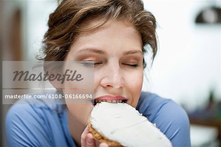 Close-up of a woman eating toast with cream spread on it