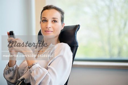 Portrait of a businesswoman text messaging on a mobile phone in an office