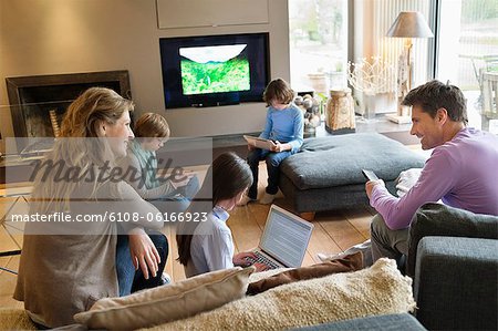 Family using electronic gadgets in a living room