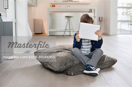 Boy hiding his face with a digital tablet Boy hiding his face with a digital tablet