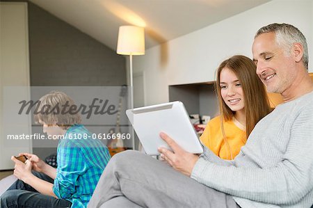 Man using a digital tablet with his daughter at home