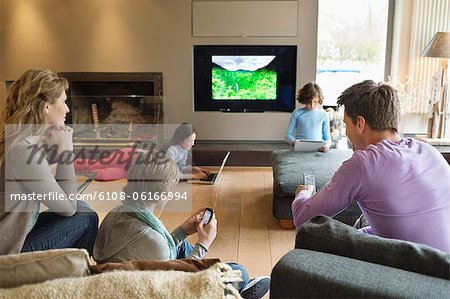 Family using electronic gadgets in a living room