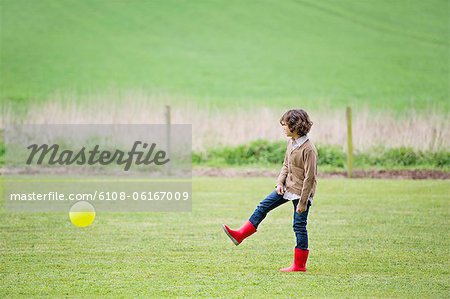 Boy playing with a ball in a field