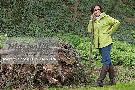 Woman standing with a shovel near a heap of rubbish