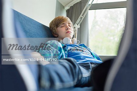 Teenage boy sleeping on a couch with headphones