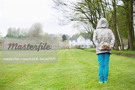 Rear view of a boy hiding a bird's nest behind his back