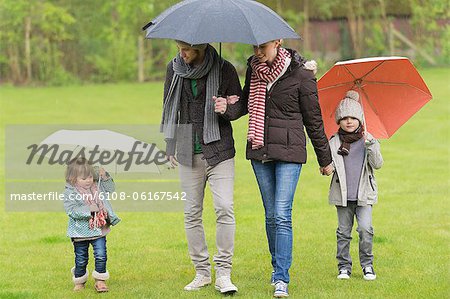 Family with umbrellas in a park