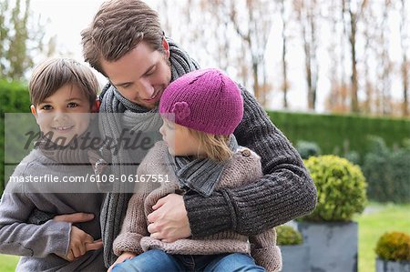 Man hugging his two children