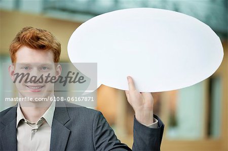 Businessman holding a speech bubble and smiling in an office