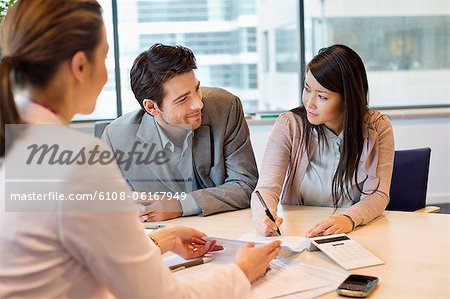 Couple signing documents with real estate agent