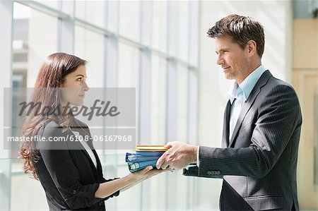 Businessmen giving files to his female colleague in an office