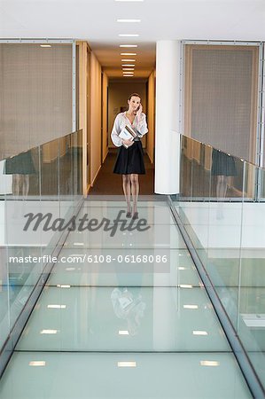 Businesswoman talking on a mobile phone in an office corridor