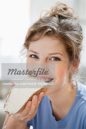 Portrait of a woman eating toast with cream spread on it