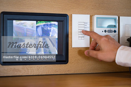 Person's hand pushing buttons for a security surveillance system at home Person's hand pushing buttons for a security surveillance system at home