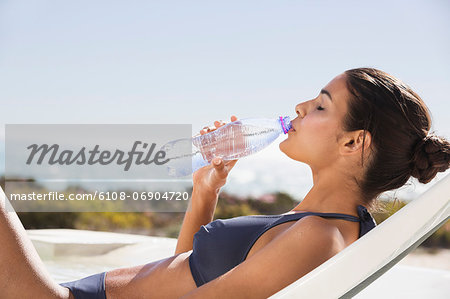 Beautiful woman drinking water on the beach