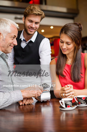 Waiter showing credit card reader to a couple on a table in a restaurant