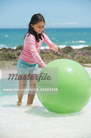 Girl playing with a fitness ball on the beach