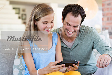 Father and daughter playing a video game and smiling at home