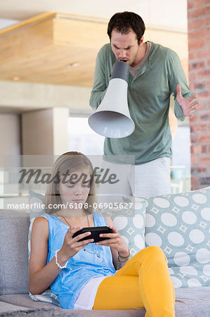 Man shouting into a megaphone at his daughter for playing video game Man shouting into a megaphone at his daughter for playing video game