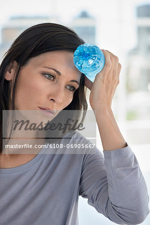 Woman holding a water bottle on her forehead