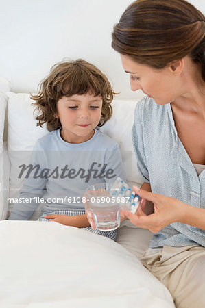 Woman giving medicine to her sick son