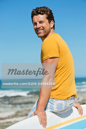 Man sitting on a surfboard on the beach