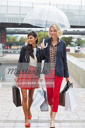 Female friends walking with shopping bags and smiling
