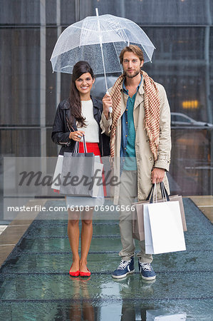 Couple standing with shopping bags during rain