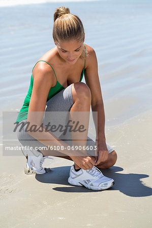 Woman tying her shoelaces on the beach