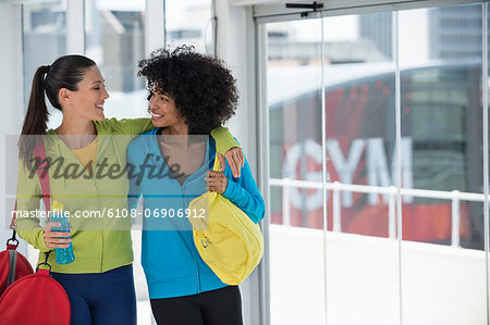 Two happy female friends carrying gym bags