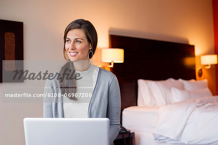 Woman using a laptop in a hotel room and smiling