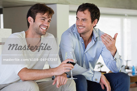 Smiling male friends with red wine