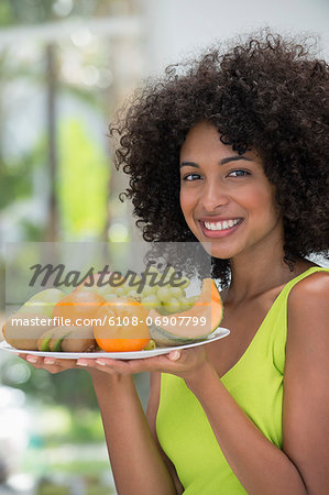 Smiling woman holding a plate of fruits