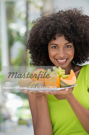 Portrait of a smiling woman holding a plate of fruits Portrait of a smiling woman holding a plate of fruits