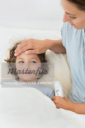 Woman touching forehead of her son looking sick Woman touching forehead of her son looking sick