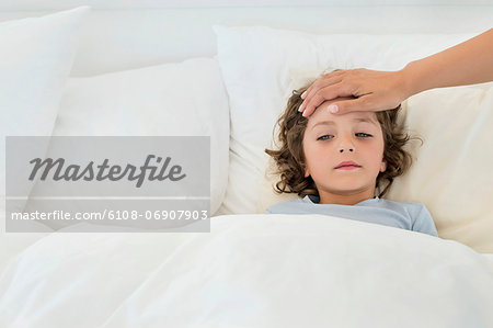 Person's hand examining fever of a boy Person's hand examining fever of a boy