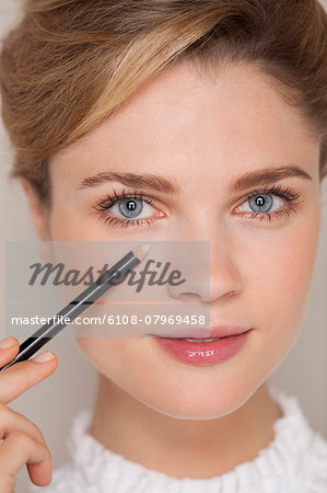 Portrait of a beautiful woman applying concealer