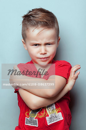 Portrait of an angry boy with arms crossed, looking toward the lens