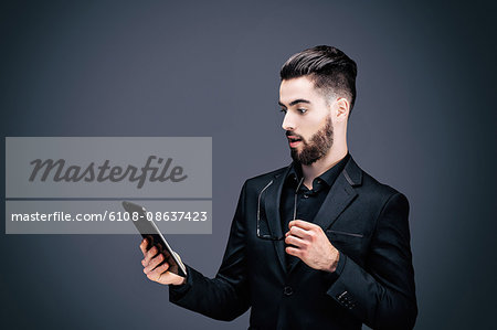 Portrait of a young shocked businessman holding a touch pad in his hands