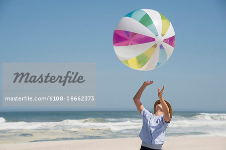 Girl playing on the beach with a ball