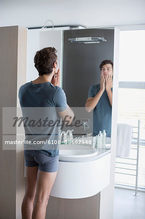 Young man applying aftershave on her face