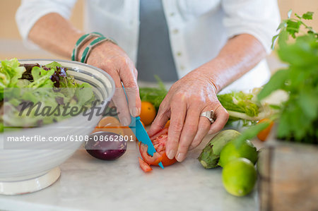 Senior woman cutting vegetables in kitchen