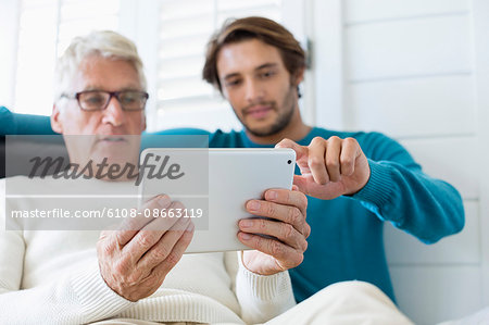 Happy father and son using digital tablet in living room