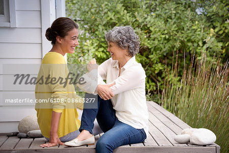 Happy mother talking with her adult daughter on porch