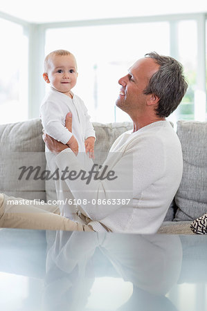 Happy father playing with his cute baby daughter at home
