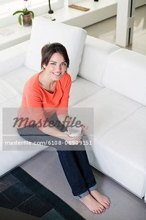 Pretty woman with a coffee/tea on the couch