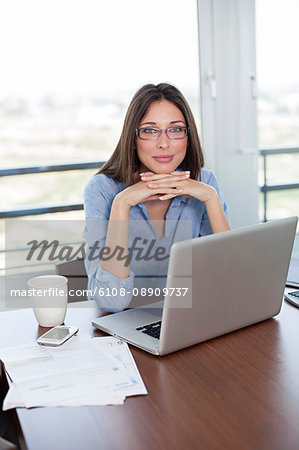 Pretty brunette woman with laptop smiling at camera